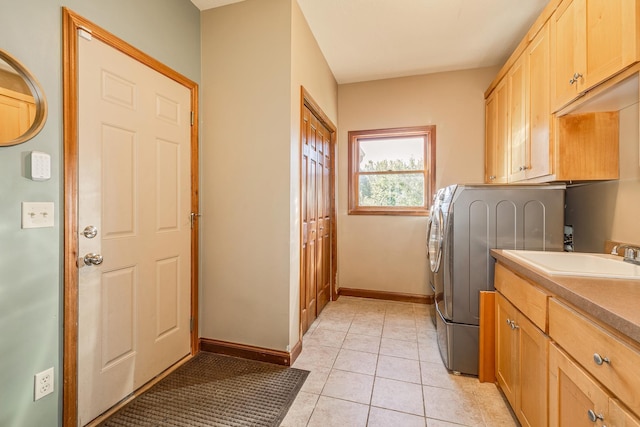 laundry room featuring light tile patterned floors, a sink, baseboards, cabinet space, and washer / clothes dryer