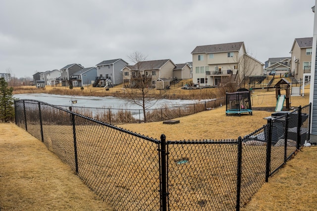 view of yard with a trampoline, fence, and a residential view