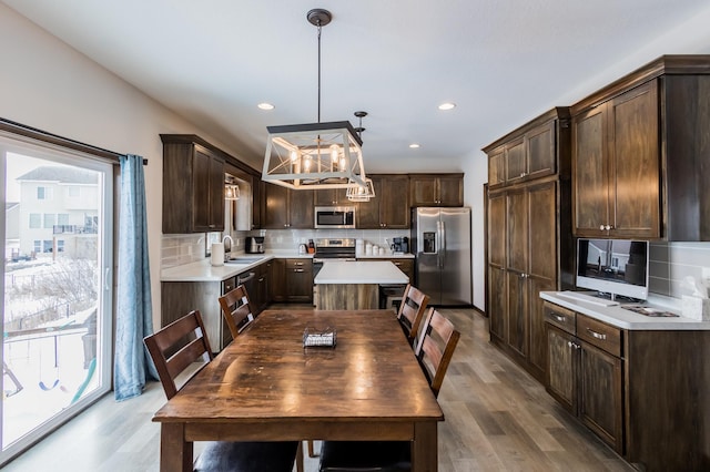 kitchen featuring dark brown cabinetry, backsplash, stainless steel appliances, light countertops, and a sink