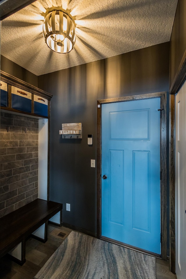 entryway with a textured ceiling, visible vents, and wood finished floors