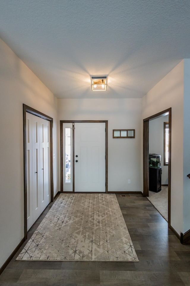 entrance foyer with a textured ceiling, wood finished floors, lofted ceiling, and baseboards