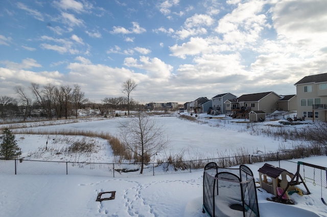 yard covered in snow featuring a residential view and fence