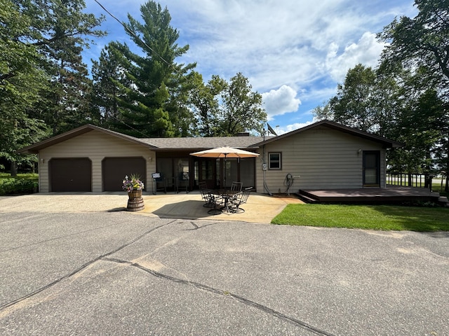 single story home featuring a garage, driveway, and a patio area