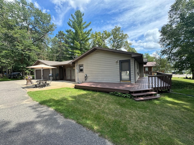 back of house with an attached garage, a yard, a patio area, and a wooden deck