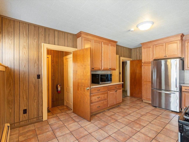 kitchen featuring freestanding refrigerator, light countertops, wood walls, and a baseboard radiator