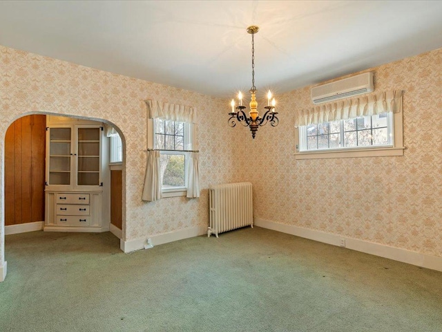 carpeted spare room featuring radiator, wallpapered walls, baseboards, and a wall mounted AC