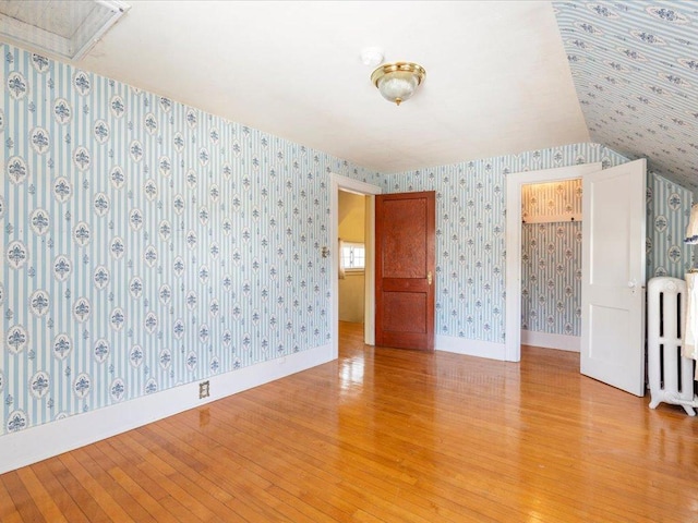 empty room featuring light wood finished floors and wallpapered walls