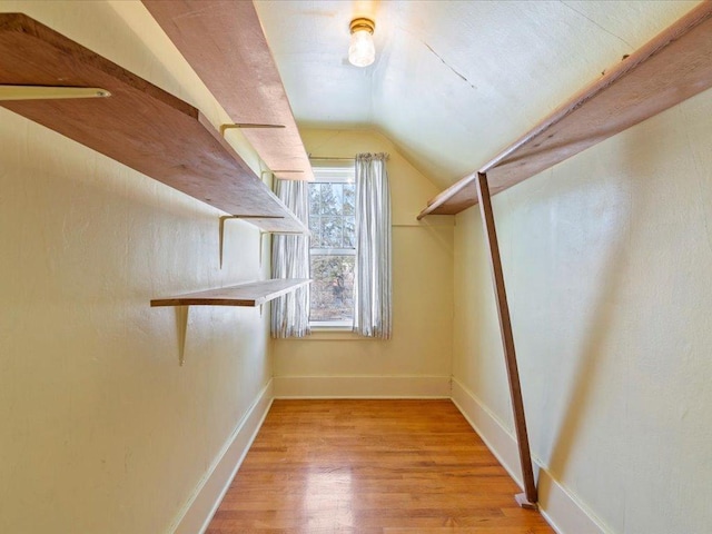 spacious closet with light wood-type flooring and vaulted ceiling