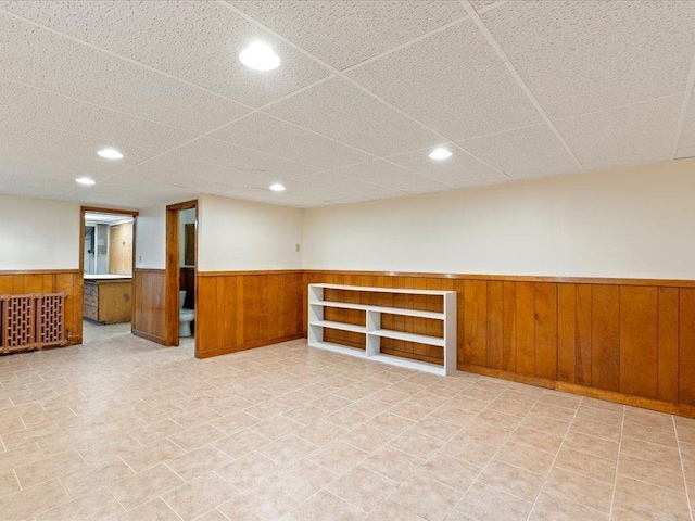 finished basement featuring wood walls, wainscoting, a paneled ceiling, and recessed lighting