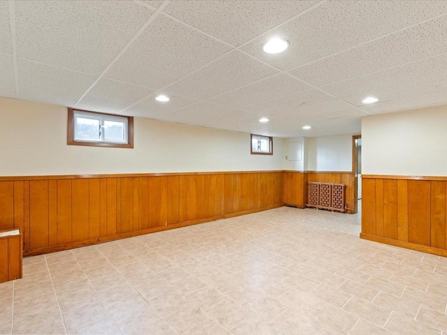 below grade area with recessed lighting, wainscoting, wooden walls, and radiator heating unit