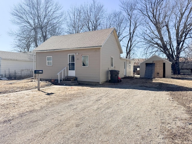 view of front of house with a shingled roof, entry steps, driveway, and an outbuilding