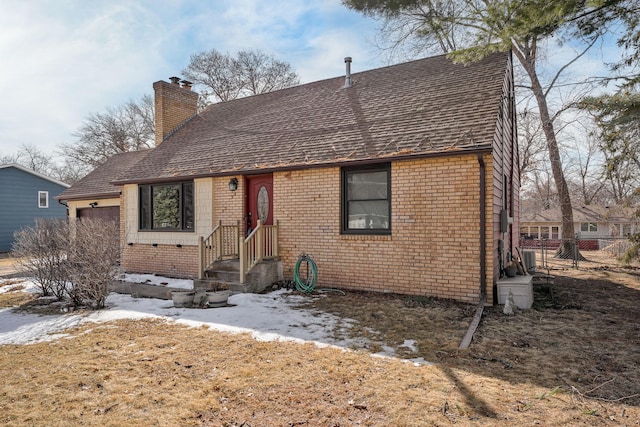 view of front of house with an attached garage, fence, brick siding, and a chimney