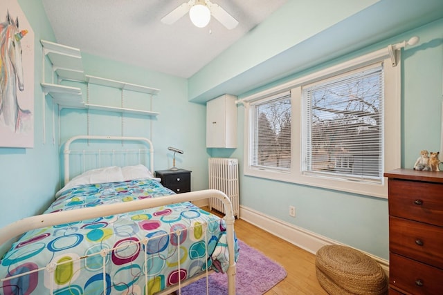 1001 Humboldt Ave W, Saint Paul, MN 55118 - bedroom featuring radiator, baseboards, light wood-type flooring, and ceiling fan