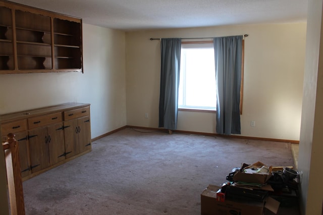 spare room featuring light carpet and baseboards