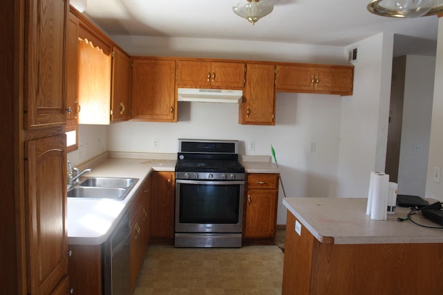 kitchen with brown cabinets, light countertops, under cabinet range hood, stainless steel range with gas cooktop, and a sink