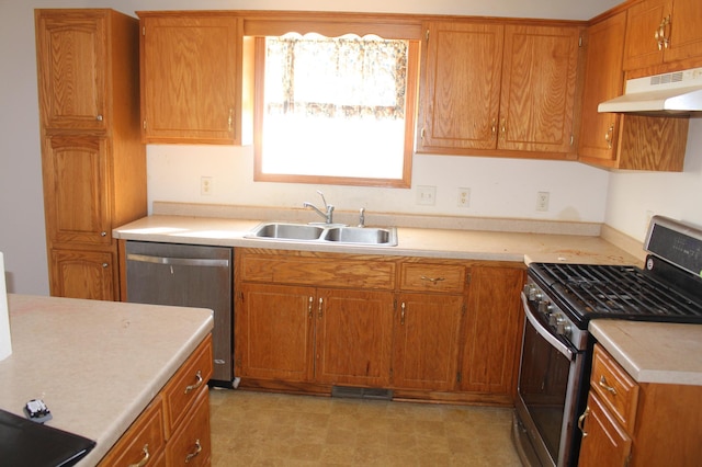 kitchen with under cabinet range hood, a sink, light countertops, appliances with stainless steel finishes, and brown cabinets