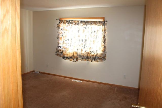 carpeted empty room featuring visible vents and baseboards