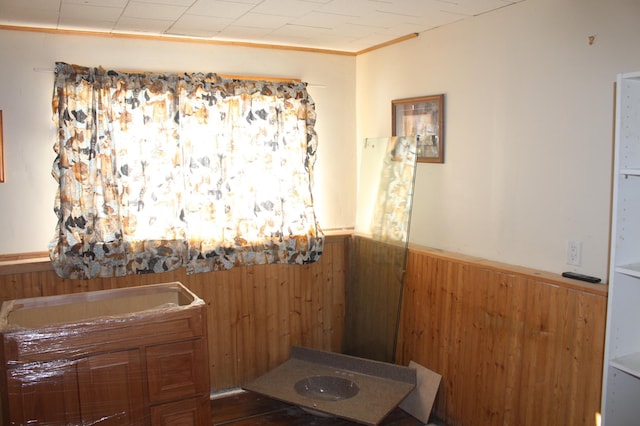 bathroom featuring a wainscoted wall, wooden walls, and crown molding