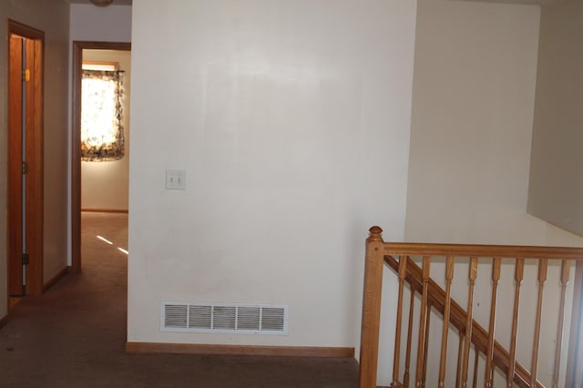 hallway with baseboards, visible vents, and an upstairs landing