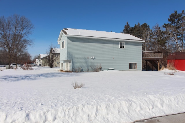 snow covered house featuring a deck and stairs