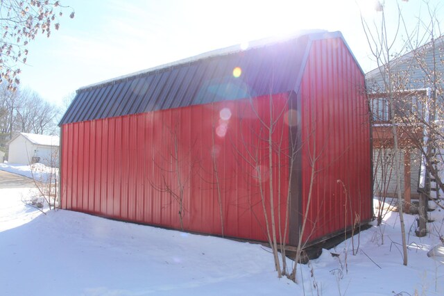 snow covered structure with an outbuilding