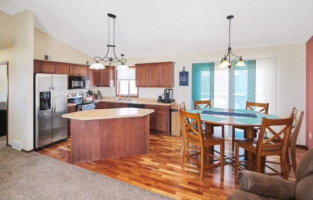 kitchen featuring appliances with stainless steel finishes, a center island, pendant lighting, and light countertops