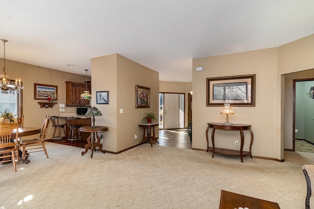 foyer with light carpet, a textured ceiling, baseboards, and a notable chandelier