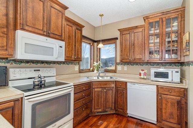 kitchen featuring dark wood-style floors, light countertops, hanging light fixtures, glass insert cabinets, and white appliances