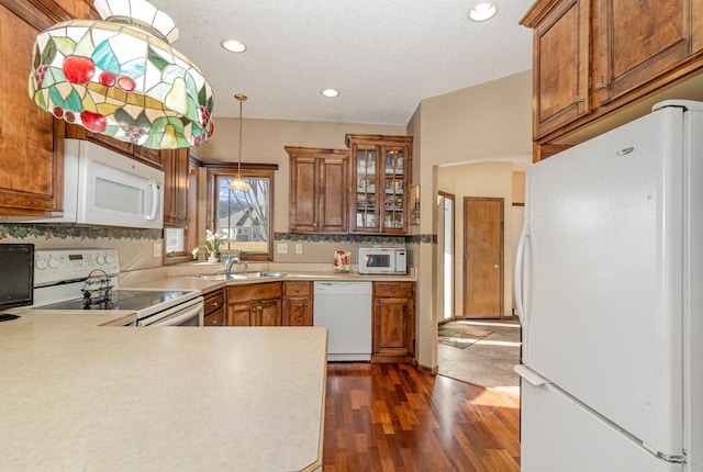 kitchen featuring decorative light fixtures, light countertops, glass insert cabinets, brown cabinetry, and white appliances