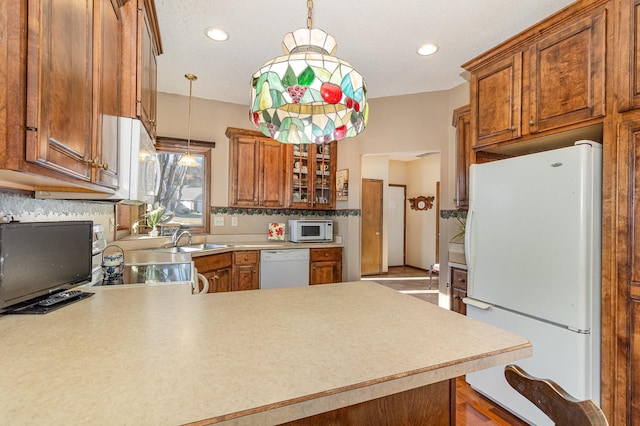 kitchen featuring white appliances, light countertops, hanging light fixtures, and a peninsula