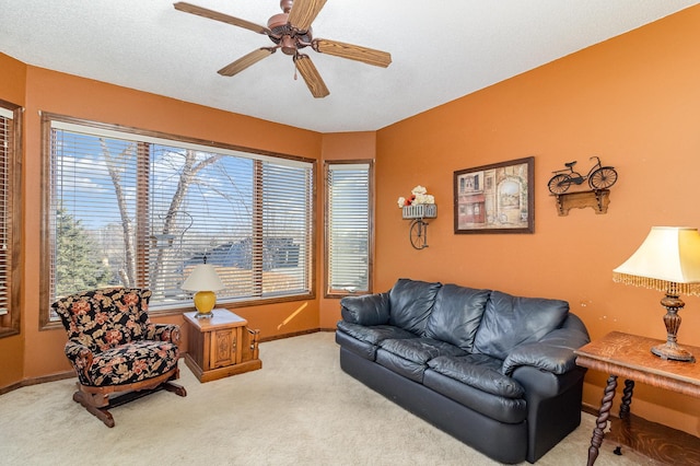 living area featuring a ceiling fan, light colored carpet, a textured ceiling, and baseboards