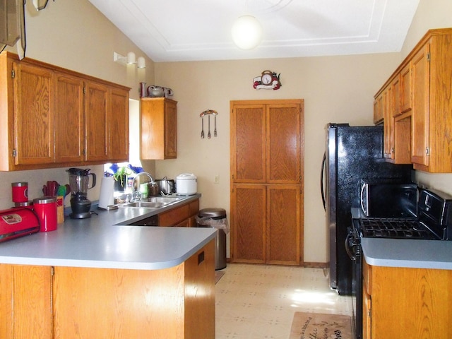 kitchen with brown cabinetry, light countertops, a sink, and a peninsula