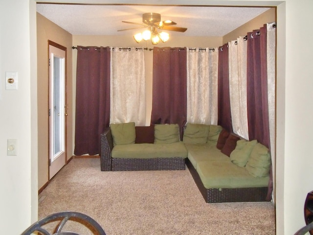 living room with ceiling fan, a textured ceiling, and light colored carpet