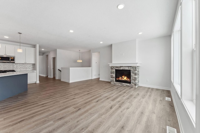 unfurnished living room featuring recessed lighting, a fireplace, visible vents, baseboards, and light wood-style floors