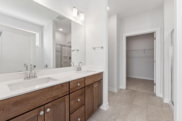 bathroom featuring a spacious closet, a sink, visible vents, and a shower stall