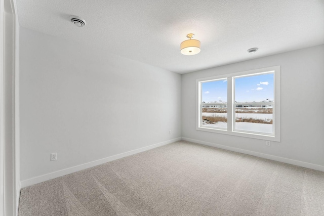 carpeted spare room featuring visible vents, baseboards, and a textured ceiling