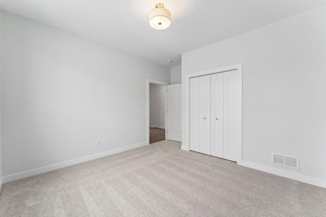 unfurnished bedroom featuring light carpet, a closet, visible vents, and baseboards