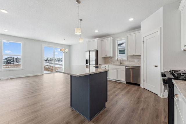 kitchen featuring pendant lighting, appliances with stainless steel finishes, white cabinets, and a center island