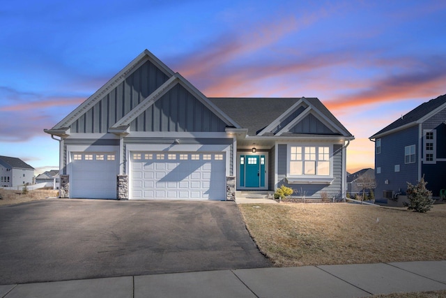 craftsman-style house featuring driveway, stone siding, central AC, board and batten siding, and a garage