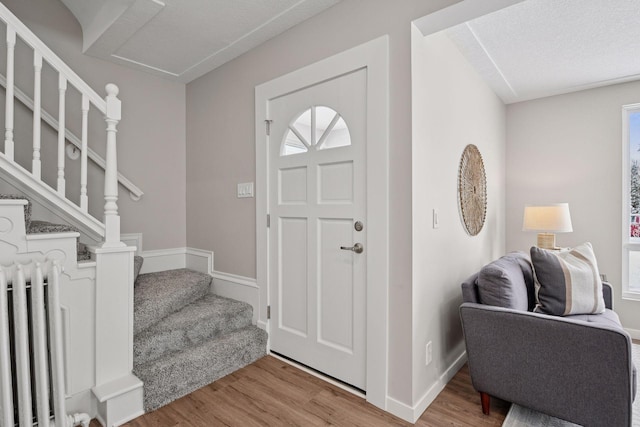 entrance foyer featuring stairs, radiator, baseboards, and wood finished floors