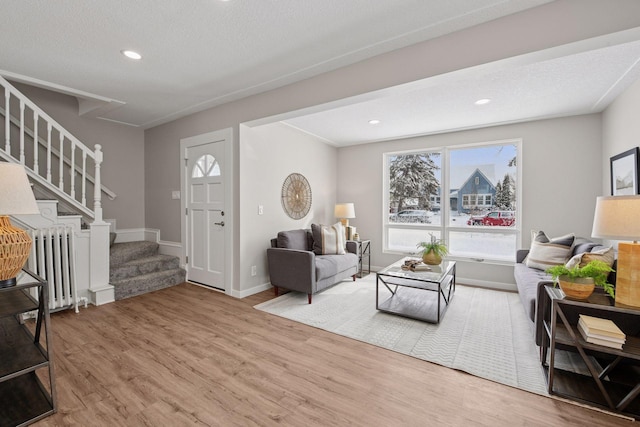 living area with recessed lighting, wood finished floors, baseboards, stairway, and radiator