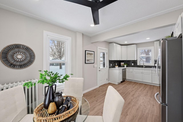 kitchen featuring a sink, white cabinets, appliances with stainless steel finishes, backsplash, and light wood finished floors