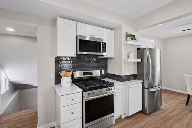 kitchen featuring light wood finished floors, tasteful backsplash, appliances with stainless steel finishes, white cabinetry, and open shelves