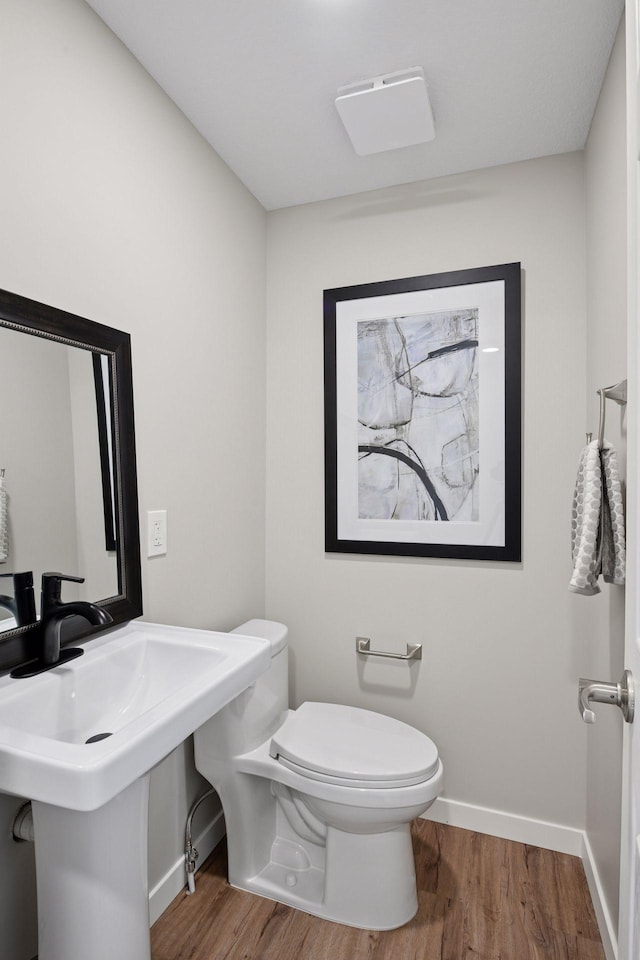 half bath featuring baseboards, toilet, and wood finished floors