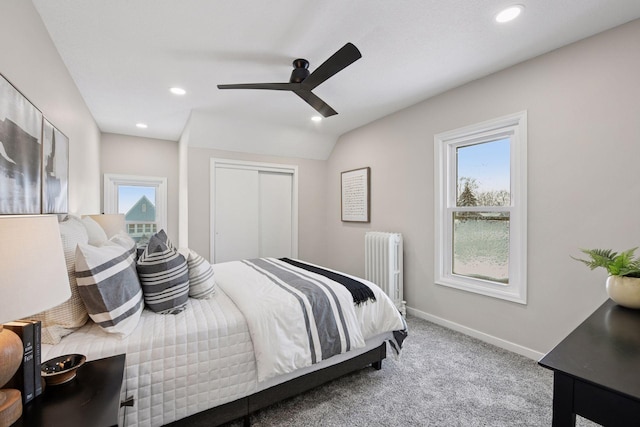 carpeted bedroom with radiator heating unit, multiple windows, baseboards, and a closet