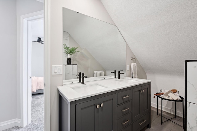 full bathroom featuring lofted ceiling, a sink, and double vanity