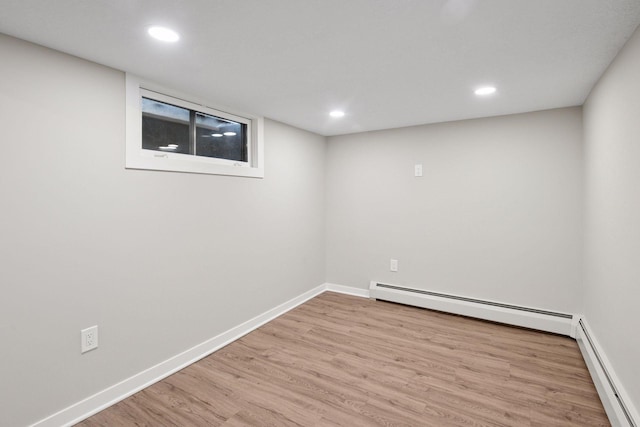 finished below grade area with baseboards, baseboard heating, and wood finished floors