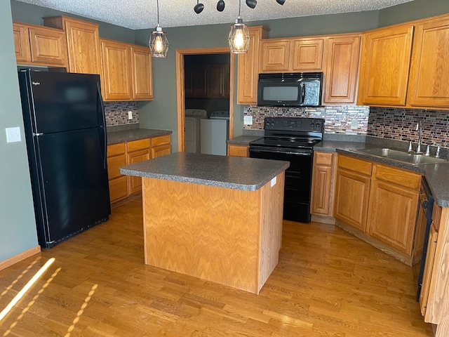 kitchen featuring independent washer and dryer, black appliances, dark countertops, and a center island