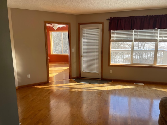 empty room with light wood-type flooring, a healthy amount of sunlight, and visible vents