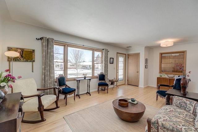 living room featuring visible vents, light wood-style flooring, and baseboards